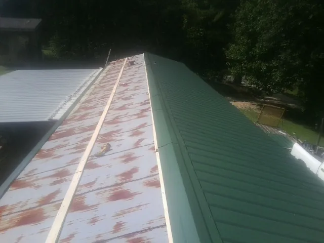 Old rusted panels beside newly installed green metal roofing — Wind Damage Roof Repair by Roofing Brothers in Hilton Head Island