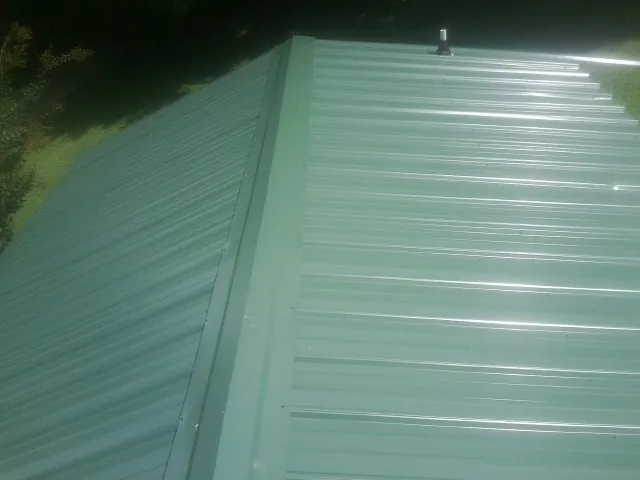 New green metal panels meeting at the ridge of a roof — Flat Roof Repair work by our crew in Hilton Head Island