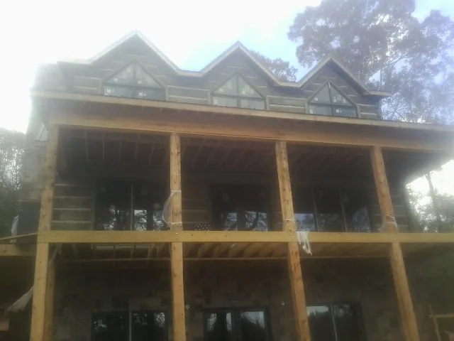 Dormers and porch framing on a large log home under construction — Roof Coating work by our crew in Hilton Head Island