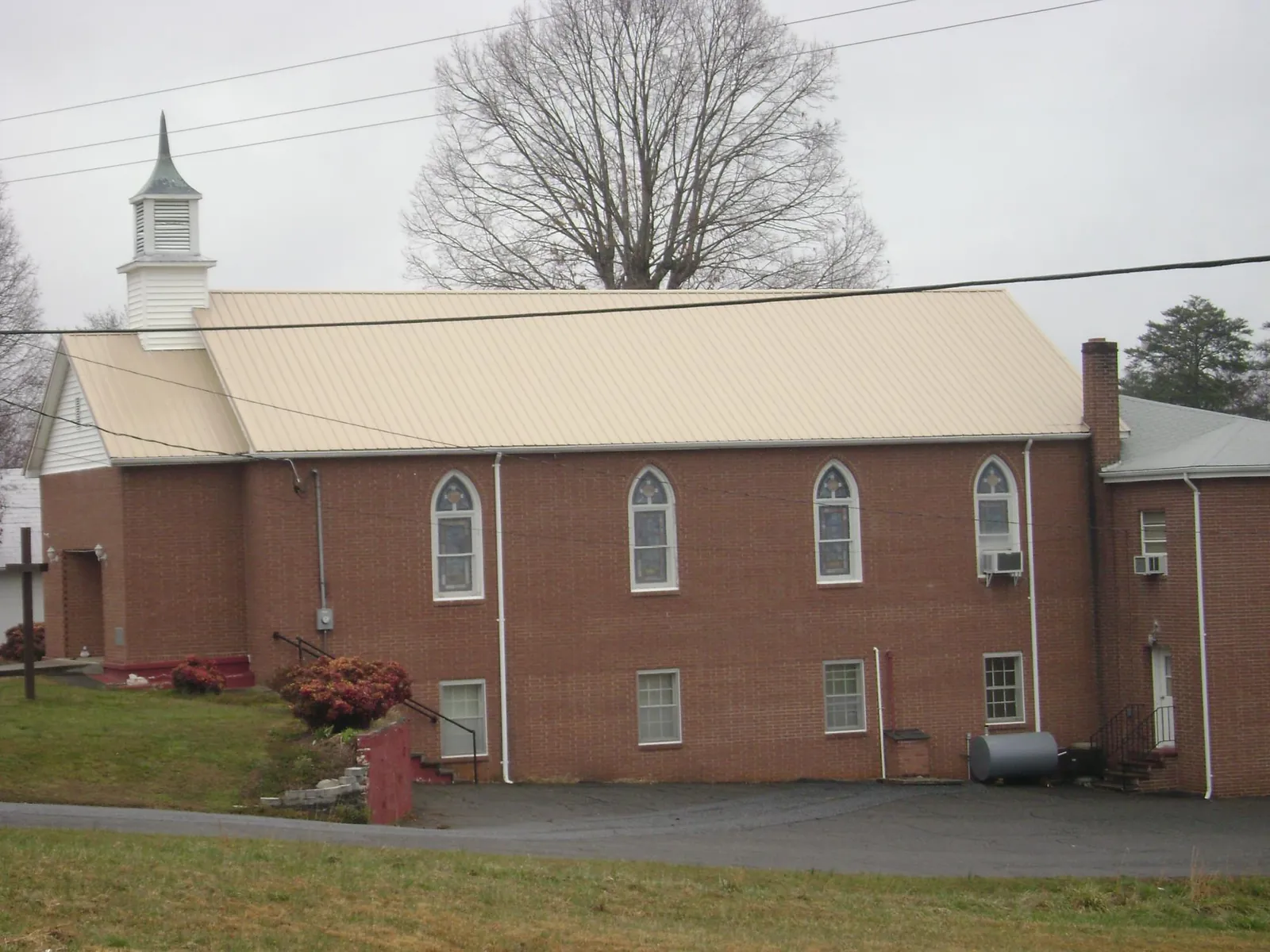 New tan metal roof on a brick church with a white steeple in Hilton Head Island