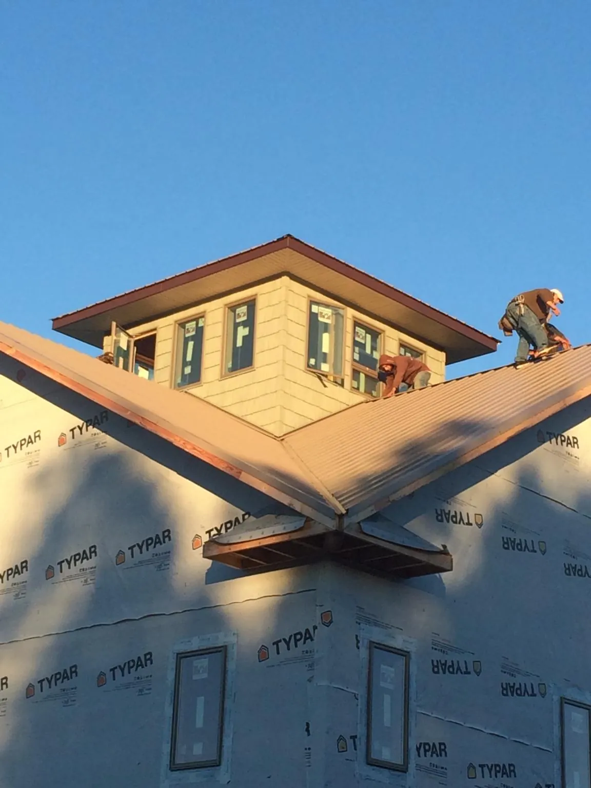 Roofers working around a rooftop cupola on a new metal roof at sunset — Roof Waterproofing in Hilton Head Island by Roofing Brothers
